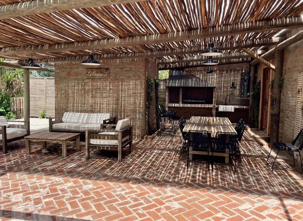 Quincho con parrilla y comedor bajo pérgola de caña