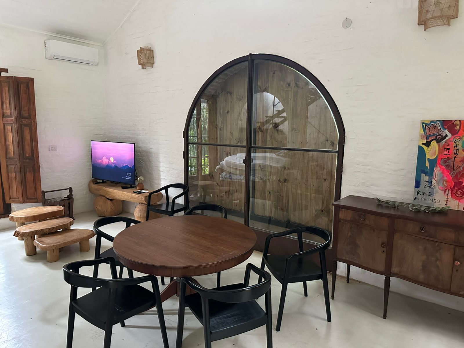 Sala con mesa redonda y ventanal arqueado